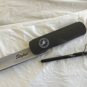 May include: A black stylus pen with a silver clip and the word "Stylus" printed on the side. The pen is in a black case with the words "Streamlight" and "National Wild Turkey Federation" printed on it.