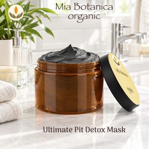 May include: A dark amber plastic jar filled with a thick black paste, topped with a black lid featuring a yellow label with the text Mia Botanica organic. The text Ultimate Pit Detox Mask is printed below the jar on the surface.