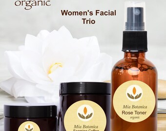 May include: A set of three organic skincare products in brown glass jars and bottles with labels that say "Mia Botanica". The products are a foaming coffee face scrub, a rose toner, and a day cream. The products are arranged on a white background with a white flower.