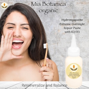 May include: A woman holding a bamboo toothbrush and smiling next to a bottle of Hydroxyapatite Extreme Overnight Repair Paste. The bottle has a white cap and a yellow label with the text "Mía Botanica organic". The image also includes the text "Remineralize and Balance".