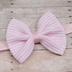 以下が含まれることがあります： ピンクと白のストライプの布製のボウヘッドバンド。ヘッドバンドは柔らかく伸縮性のある素材で作られており、どんな服装にもスタイルを加えるのに最適です。