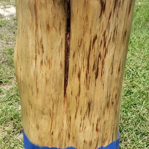 May include: A wooden stump with a natural wood finish and a blue painted base. The stump is a natural, rustic style and would be a great addition to a home decor or garden.