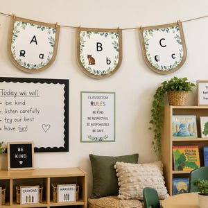Op de afbeelding: Een klaslokaal wanddecoratie met drie hangende wimpels met de letters A, B en C, een whiteboard met de tekst Today we will, een Classroom Rules bord, een letterbord met BE KIND en planken met boeken en gelabelde opbergbakken.