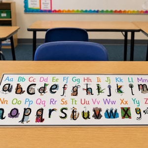 Könnte beinhalten: Eine rechteckige Schreibtischunterlage mit dem Alphabet in Groß- und Kleinbuchstaben. Jeder Kleinbuchstabe ist mit einer einzigartigen Figur oder einem Objekt illustriert, während die Großbuchstaben in verschiedenen Farben gedruckt sind.