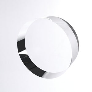 May include: A clear glass ring, or circle, with a smooth, polished surface. The ring is thick and has a slight bevel on the edge.