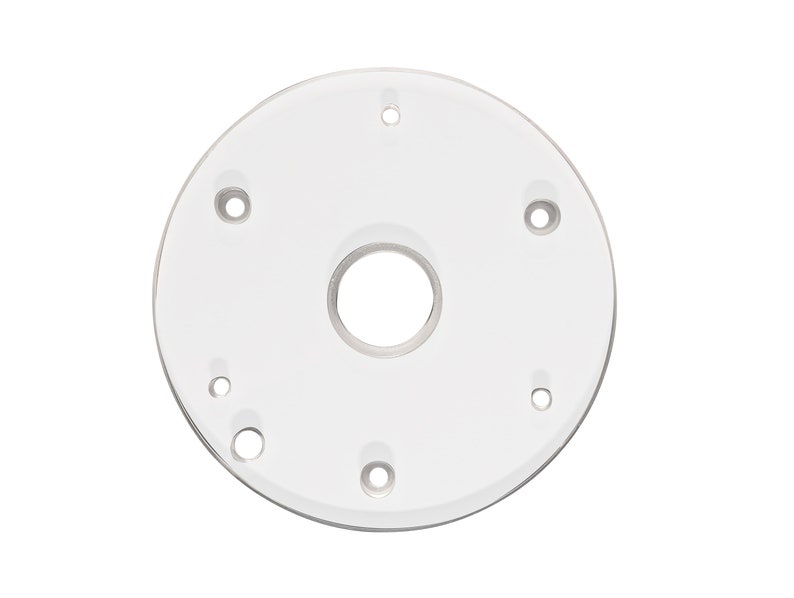 Pode incluir: Um gabarito de roteador de pl&aacute;stico branco com v&aacute;rios furos para montagem e um furo central grande para a fresa.