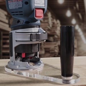 May include: A blue and grey Colt router with a red power switch. The tool has a clear plastic base and a black handle. The image is taken on a wooden surface.