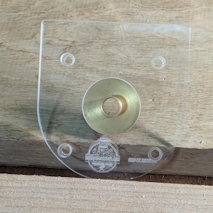 May include: A clear plastic template with four holes and a brass ring in the centre. The template has the text "The Router Workshop" and "RIP-CLASSIC" printed on it.