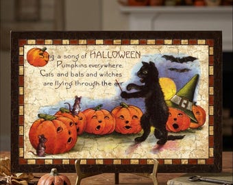 May include: A rectangular Halloween-themed sign featuring a black cat wearing a green witch hat, surrounded by orange jack-o'-lanterns and small mice. The text reads: Sing a song of HALLOWEEN, Pumpkins everywhere; Cats and bats and witches are flying through the air.