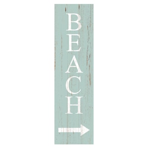 May include: A rectangular wooden sign with a distressed, light blue background. The word "BEACH" is vertically printed in white capital letters, with a white arrow pointing right at the bottom. The sign has a rustic, weathered appearance.