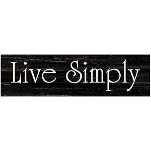 May include: Black wooden sign with white text that reads "Live Simply".