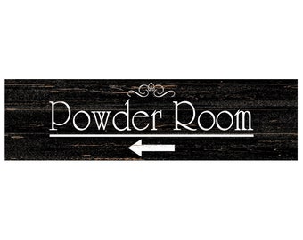 May include: A rectangular wooden sign with the words "Powder Room" in white, with an arrow pointing left. The sign has a dark, distressed wood grain background and decorative flourishes above the text.