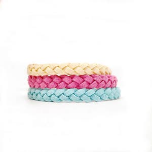 May include: Three braided bracelets in light blue, pink, and cream colors. The bracelets are stacked on top of each other.