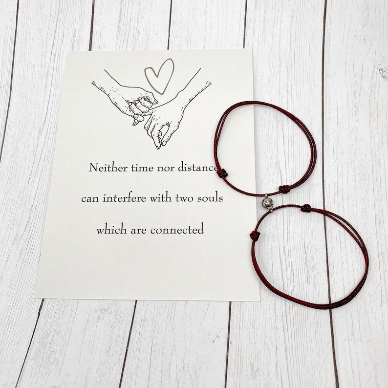 Magnetic matching couple bracelets with printed gift card displayed flat lay