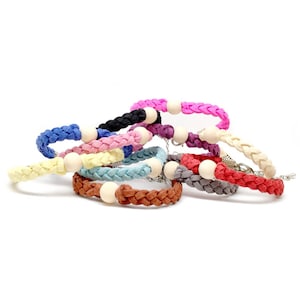 May include: A set of eight braided bracelets with wooden beads. The bracelets are in various colors, including pink, blue, yellow, red, and brown.