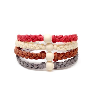 May include: A set of four braided bracelets with wooden beads. The bracelets are red, cream, brown, and gray.