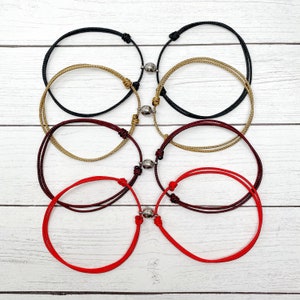 Puede incluir: Cuatro pares de pulseras de la amistad con cierres magn&eacute;ticos. Las pulseras son rojas, burdeos, doradas y negras.
