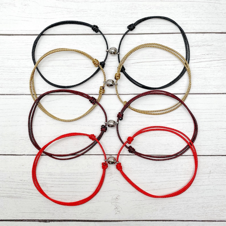 Puede incluir: Cuatro pares de pulseras de la amistad con cierres magn&eacute;ticos. Las pulseras son rojas, burdeos, doradas y negras.