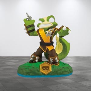 May include: A green and yellow action figure of a frog-like creature with a weapon. The figure has brown pants, a yellow and black vest, and a green tail. It stands on a green base with a gold emblem.