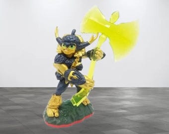 May include: A Skylanders action figure of a character with a blue and gold helmet, yellow hair, and a yellow axe. The figure is posed on a green and red base, with a light background.