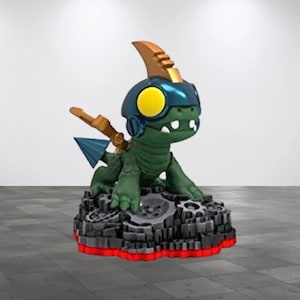 May include: A green and blue action figure of a dragon-like creature with a yellow eye, wearing a helmet and armor. The figure is on a gray and black base with a red border, and has a gold fin.