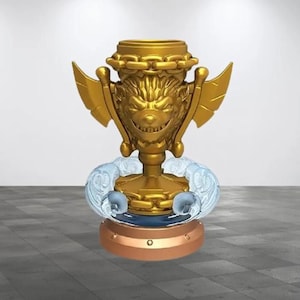 May include: A gold trophy with a snarling, cartoonish creature face on the front. The trophy is on a blue base with a gold chain around the base. The base is on a brown platform.