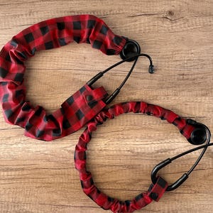 May include: Two black stethoscope tubes with red and black plaid fabric covers. The fabric covers are elastic and can be adjusted to fit different sizes of stethoscopes.