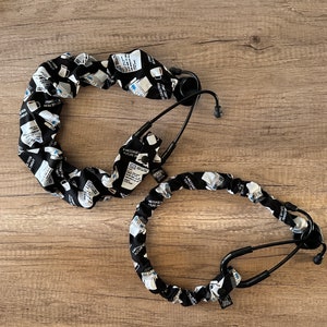 May include: Two black and white patterned stethoscope cords with black earpieces. The cords are made of fabric and have a message printed on them. The message reads "A message in a bottle, future doctor".