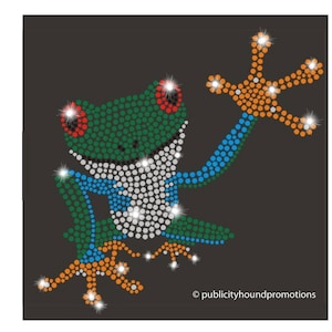 May include: A rhinestone frog design on a dark background. The frog is green, white, blue, and orange, with sparkling accents. The frog's eyes are red. The design is made of small, round rhinestones. The text "publicityhoundpromotions" is at the bottom.