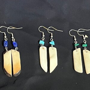 May include: Four pairs of dangle earrings with different colored stones. Each pair features a long, rectangular, white bone-like pendant.