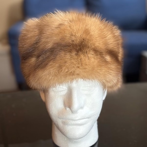 May include: A brown fur hat with a wide brim. The hat is made of soft, fluffy fur and has a classic design.