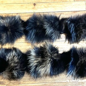 May include: Six black and grey fur pom poms with black straps. The pom poms are arranged in two rows of three.