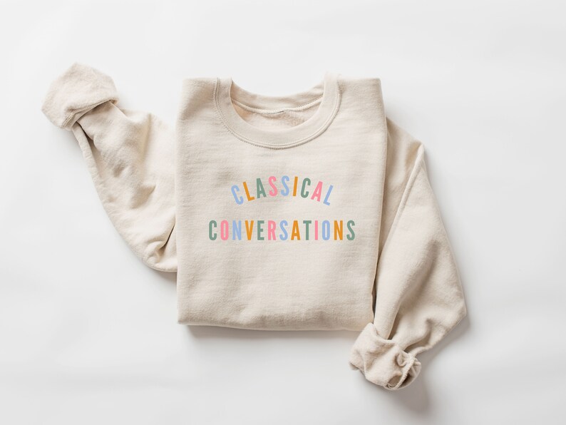 May include: A beige sweatshirt with the text "CLASSICAL CONVERSATIONS" printed in rainbow colors.