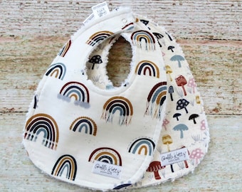 Può includere: Due bavaglini per neonati bianchi con stampa arcobaleno e funghi. I bavaglini sono realizzati in tessuto morbido e assorbente e hanno un retro in spugna. I bavaglini sono etichettati "Belli Kitti's Boutique".