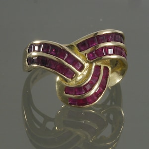 May include: A gold ring with a knot design set with red rubies.