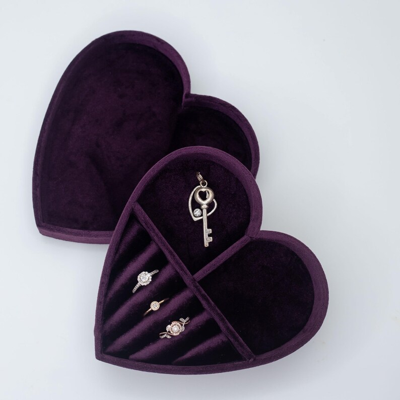 May include: A purple velvet heart-shaped jewelry box with compartments for rings and a pendant. The box is open and the compartments are visible.