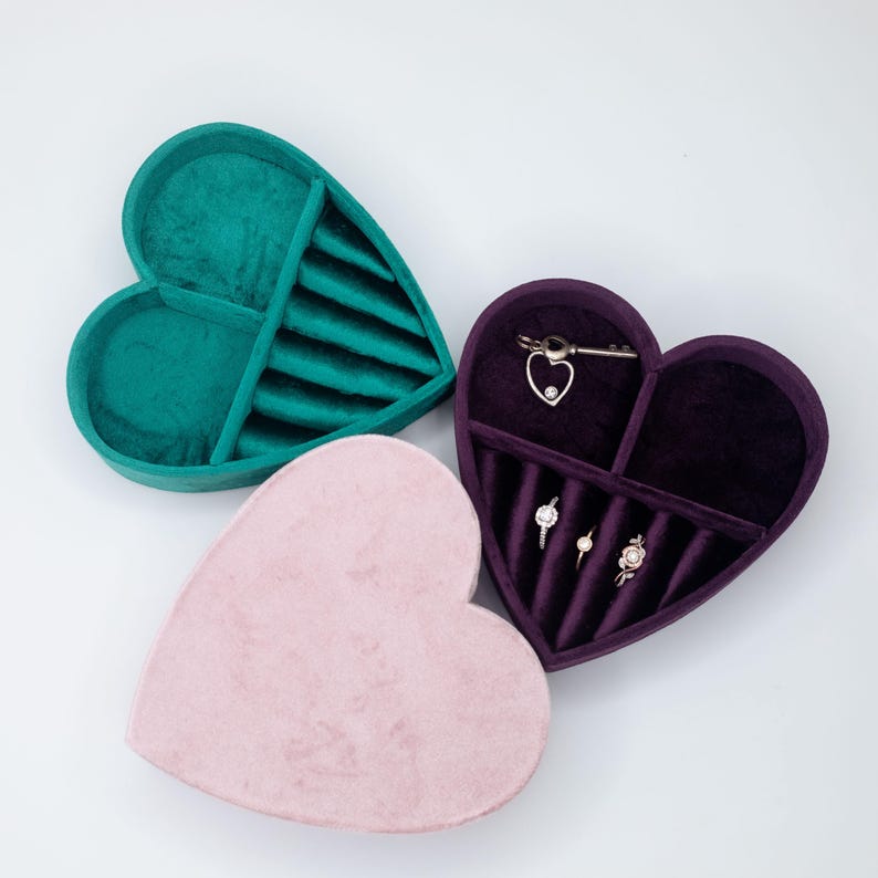 May include: Three heart-shaped velvet jewelry boxes in pink, green, and purple. The boxes have compartments for rings, earrings, and necklaces.