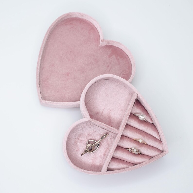 May include: A pink velvet heart-shaped jewelry box with compartments for rings and a larger compartment for necklaces or bracelets.