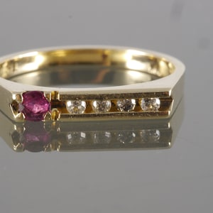 May include: A gold band ring with a single ruby gemstone and a row of smaller diamonds.