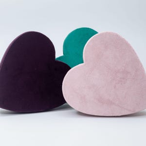 May include: Three heart-shaped velvet boxes in purple, pink, and teal.