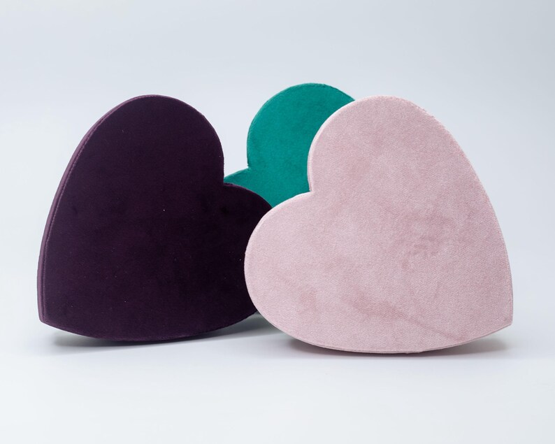 May include: Three heart-shaped velvet boxes in purple, pink, and teal.