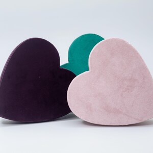 May include: Three heart-shaped boxes made of velvet. The boxes are in shades of purple, pink, and green.
