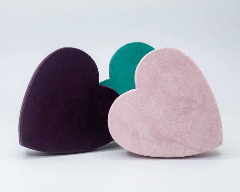 May include: Three heart-shaped boxes made of velvet. The boxes are in shades of purple, pink, and green.
