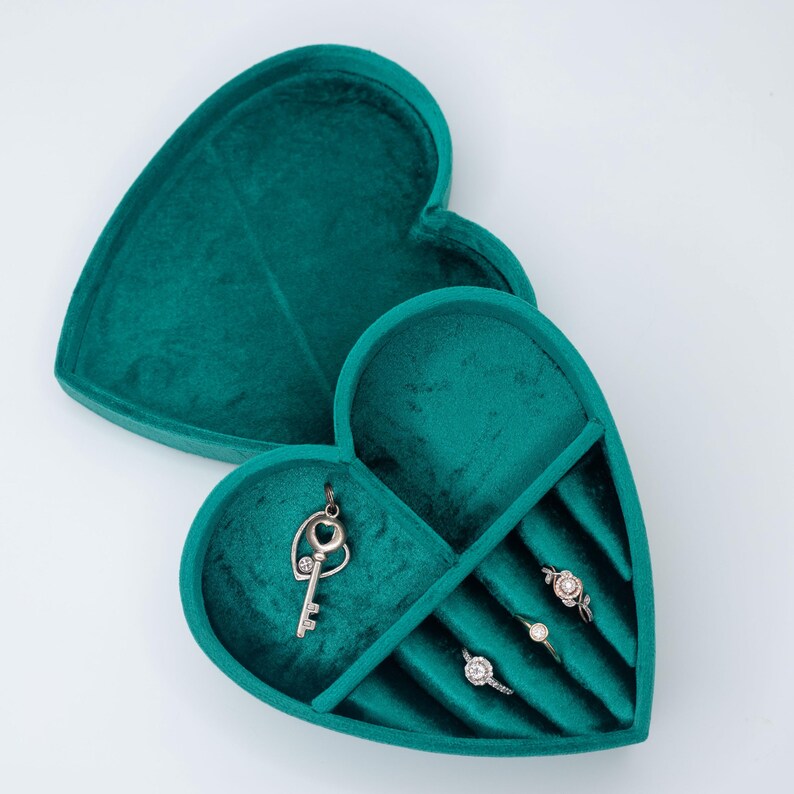 May include: A teal velvet heart-shaped jewelry box with a key charm and four ring slots.