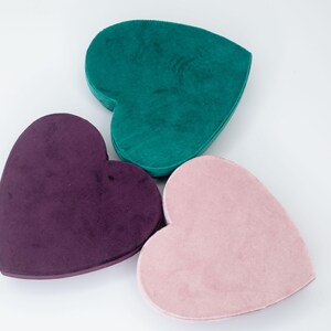 May include: Three heart-shaped boxes made of velvet. The boxes are in shades of teal, purple, and pink.