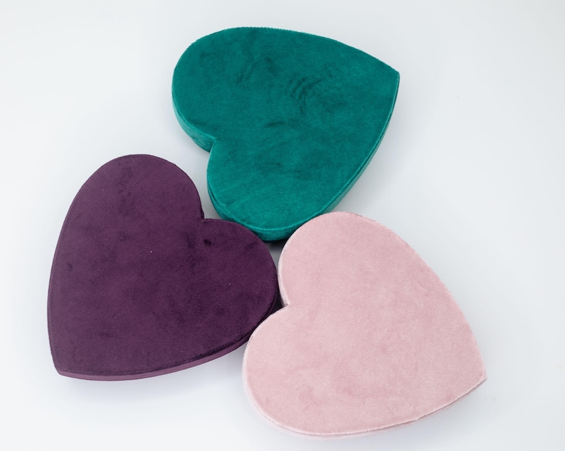 May include: Three heart-shaped boxes made of velvet. The boxes are in shades of teal, purple, and pink.