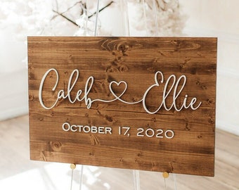 May include: A rustic wooden wedding sign with the names "Caleb & Ellie" in white cursive script and the date "October 17, 2020" below.