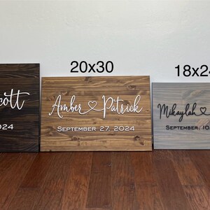 May include: Four wooden signs of varying sizes, each with names and dates. The largest is 24x36 inches, dark brown, with "Jessica Scott" and "September 7, 2024." Other signs are 20x30, 18x24, and 12x18 inches.