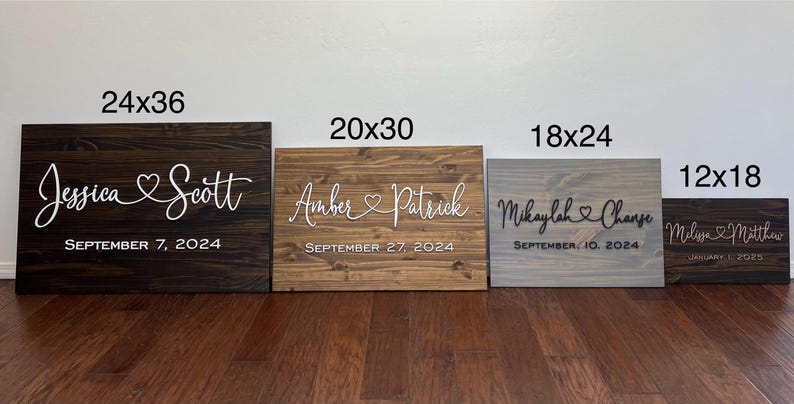 May include: Four wooden signs of varying sizes, each with names and dates. The largest is 24x36 inches, dark brown, with "Jessica Scott" and "September 7, 2024." Other signs are 20x30, 18x24, and 12x18 inches.