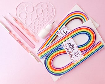 May include: A rainbow paper quilling kit with tools and glue. The kit includes 500 strips of paper in 10 colors, a heart-shaped tool, a pair of tweezers, a stylus, a brush, and a bottle of glue. The kit is packaged in a clear plastic bag with a label that says "Tulla Viktor Quilling Strips".